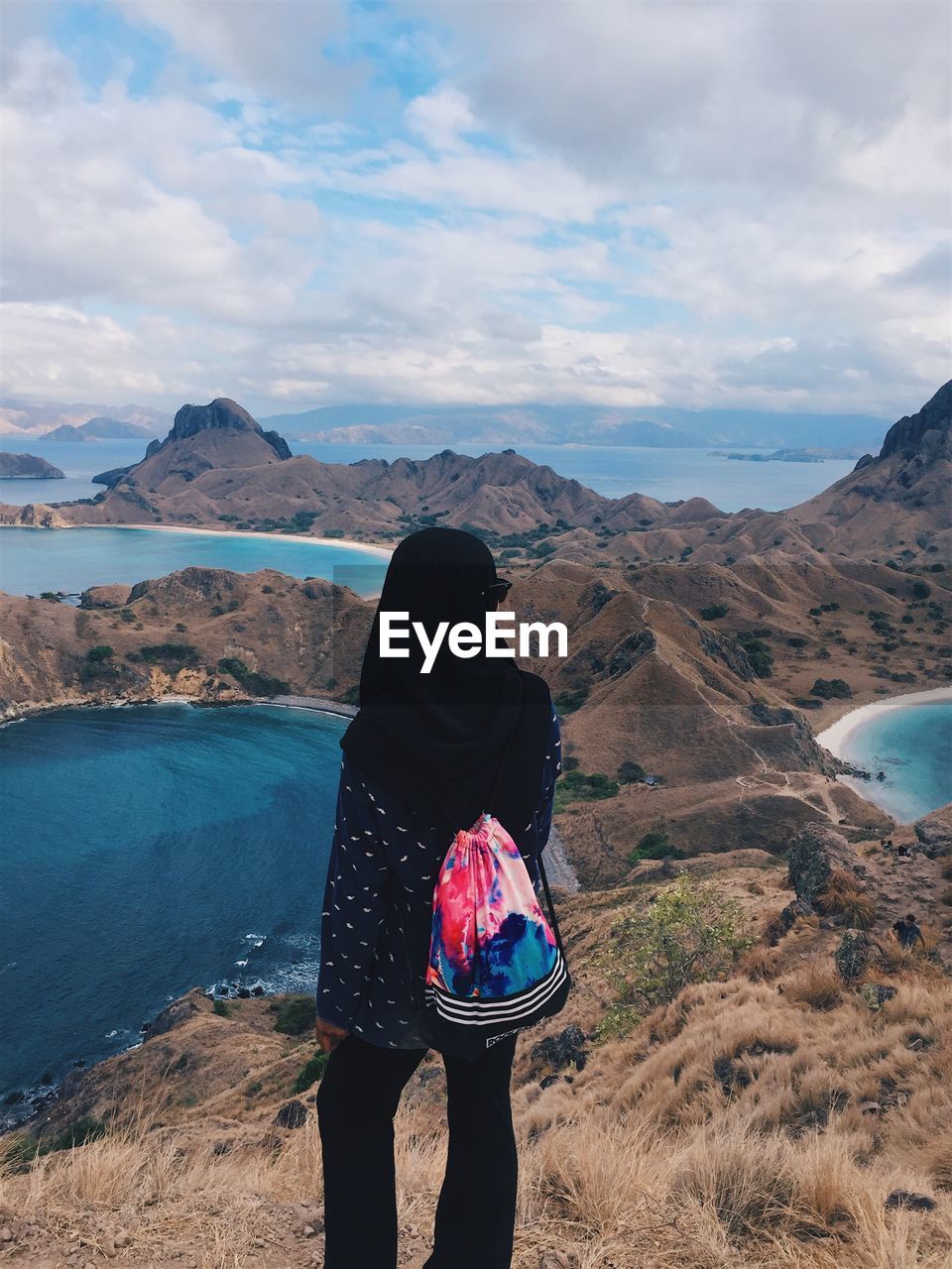 Rear view of woman standing on mountain against sky