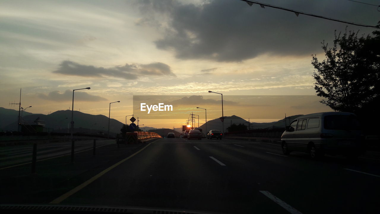 Cars on road against sky during sunset