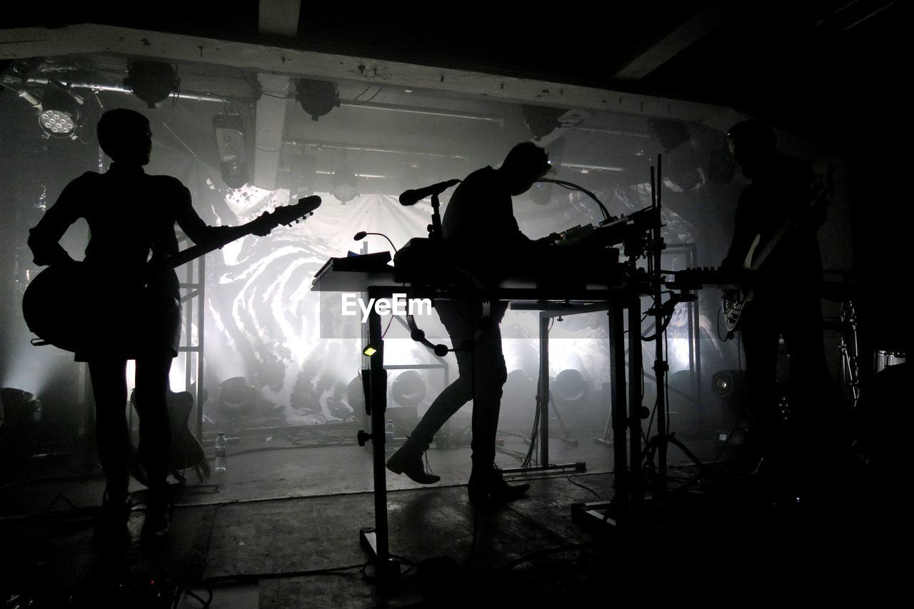 SILHOUETTE MEN PLAYING GUITAR AT MUSIC CONCERT