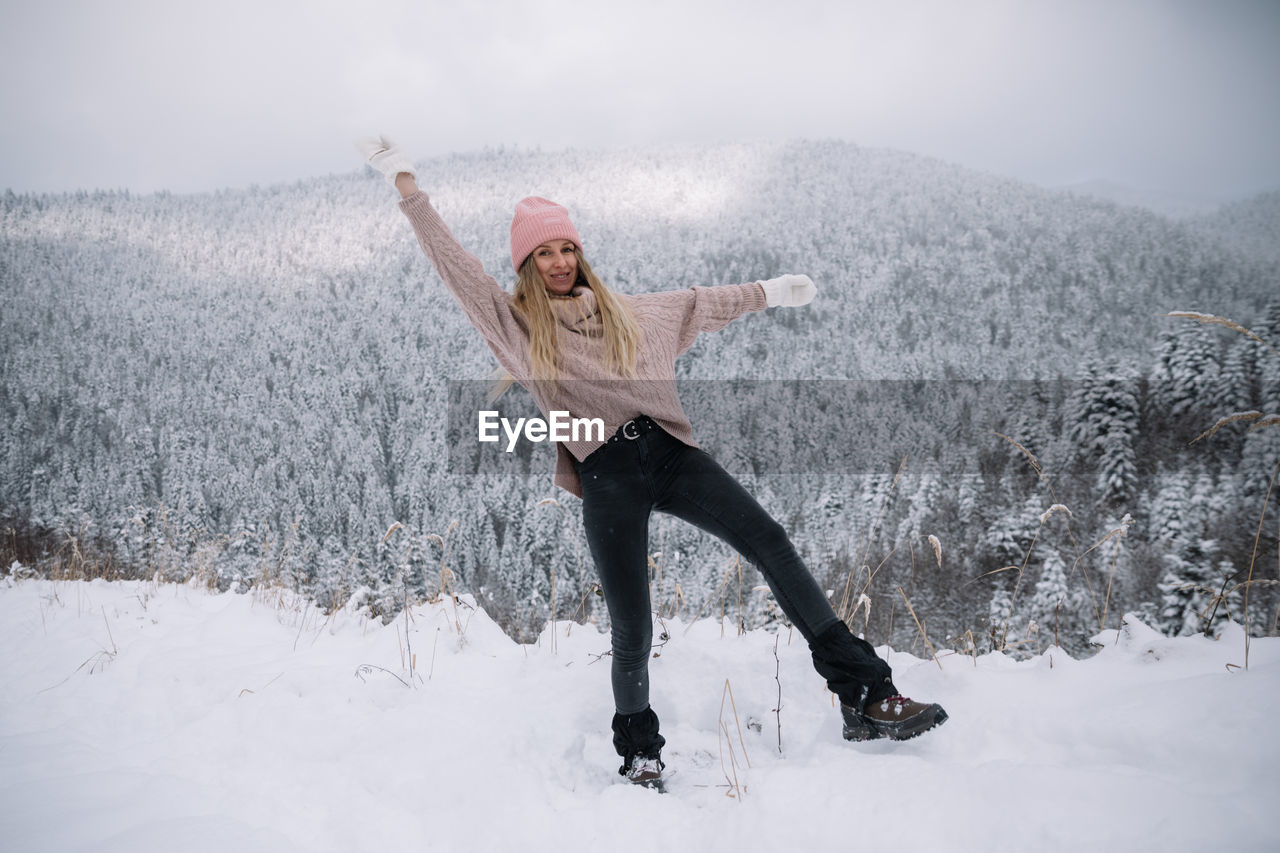 Woman standing on snow covered land during winter