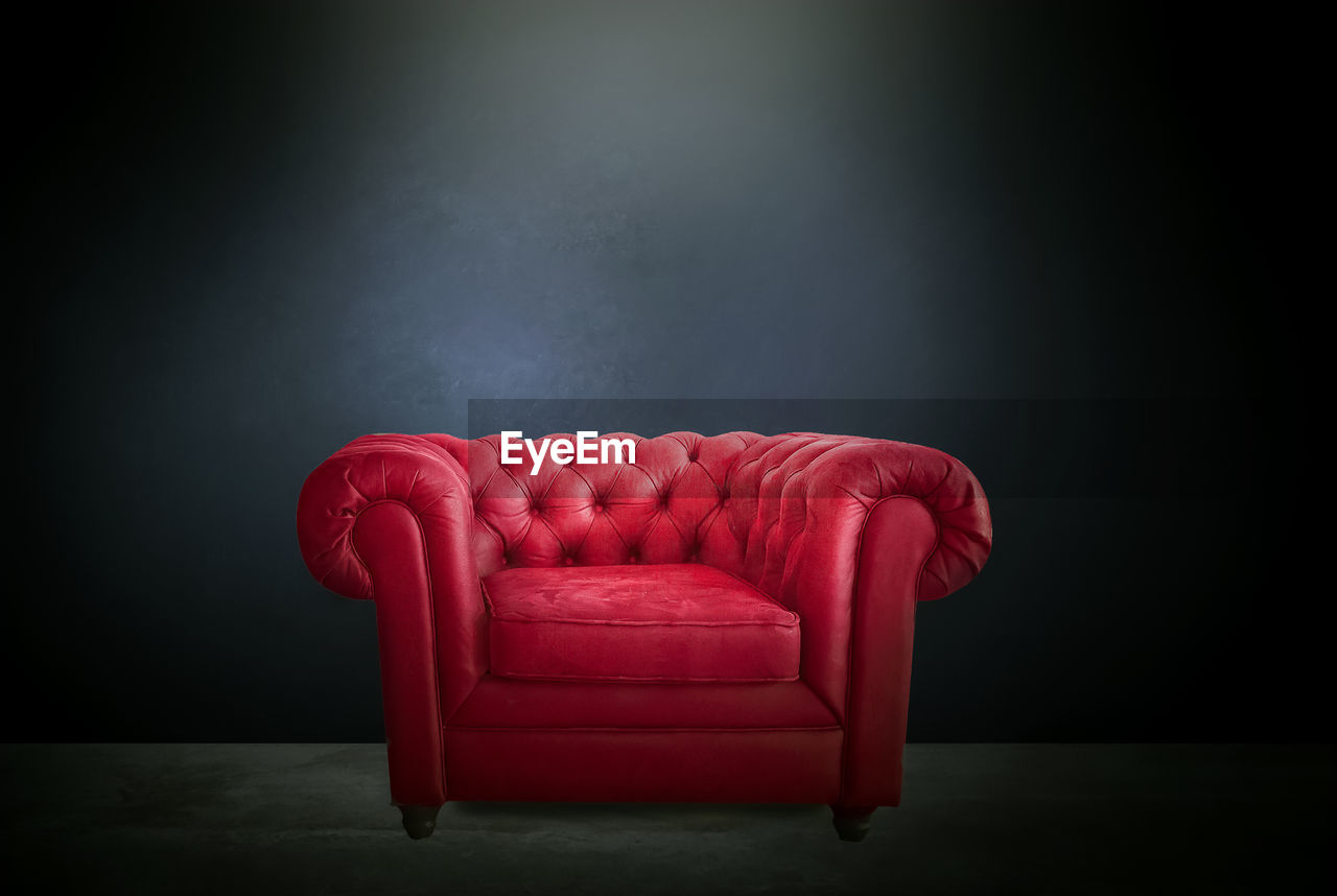 EMPTY CHAIR AGAINST RED WALL