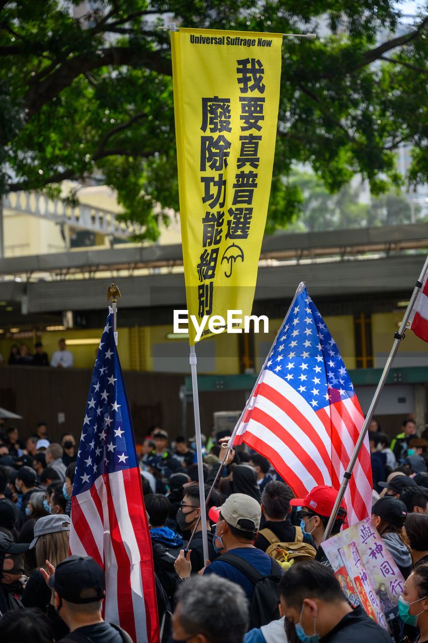 GROUP OF PEOPLE IN FRONT OF FLAGS AT CITY