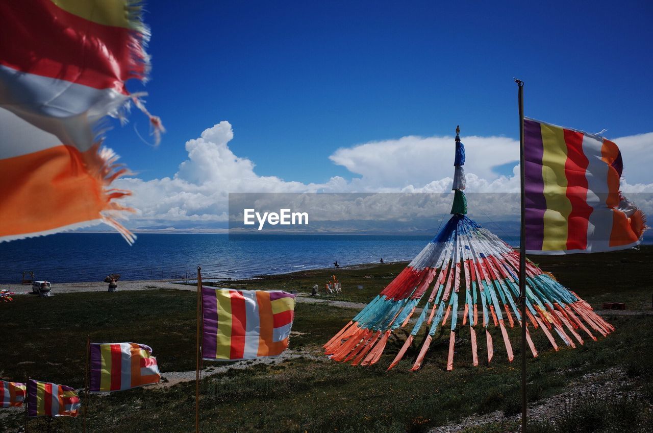 Multi colored flags on beach against sky