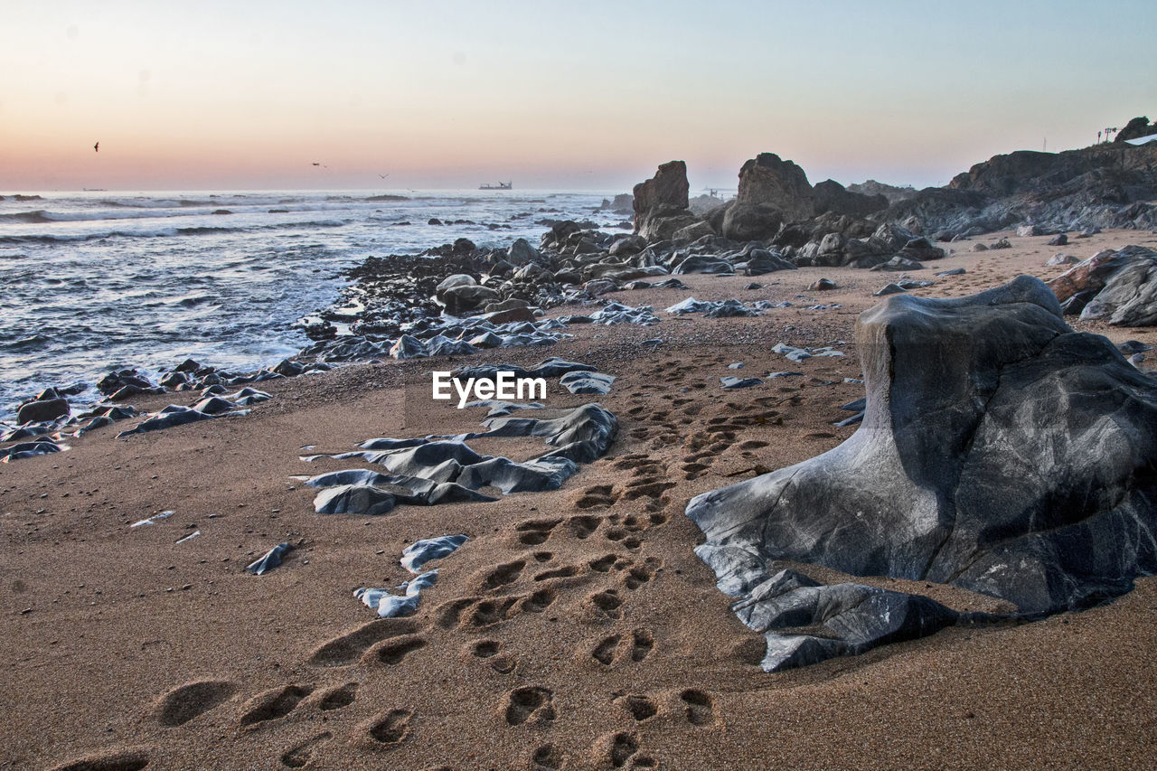 SCENIC VIEW OF ROCKS ON BEACH AGAINST SKY