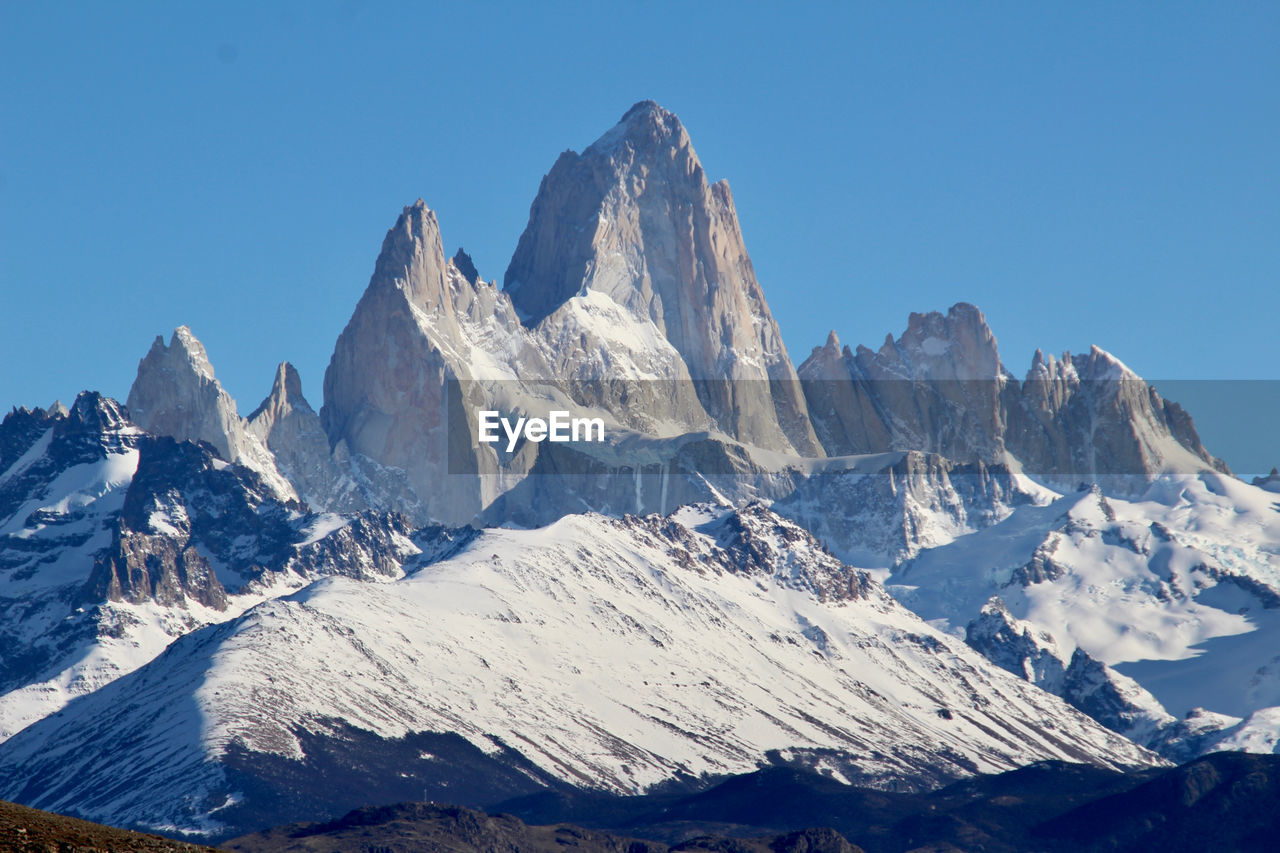 Scenic view of snowcapped mountains against clear blue sky