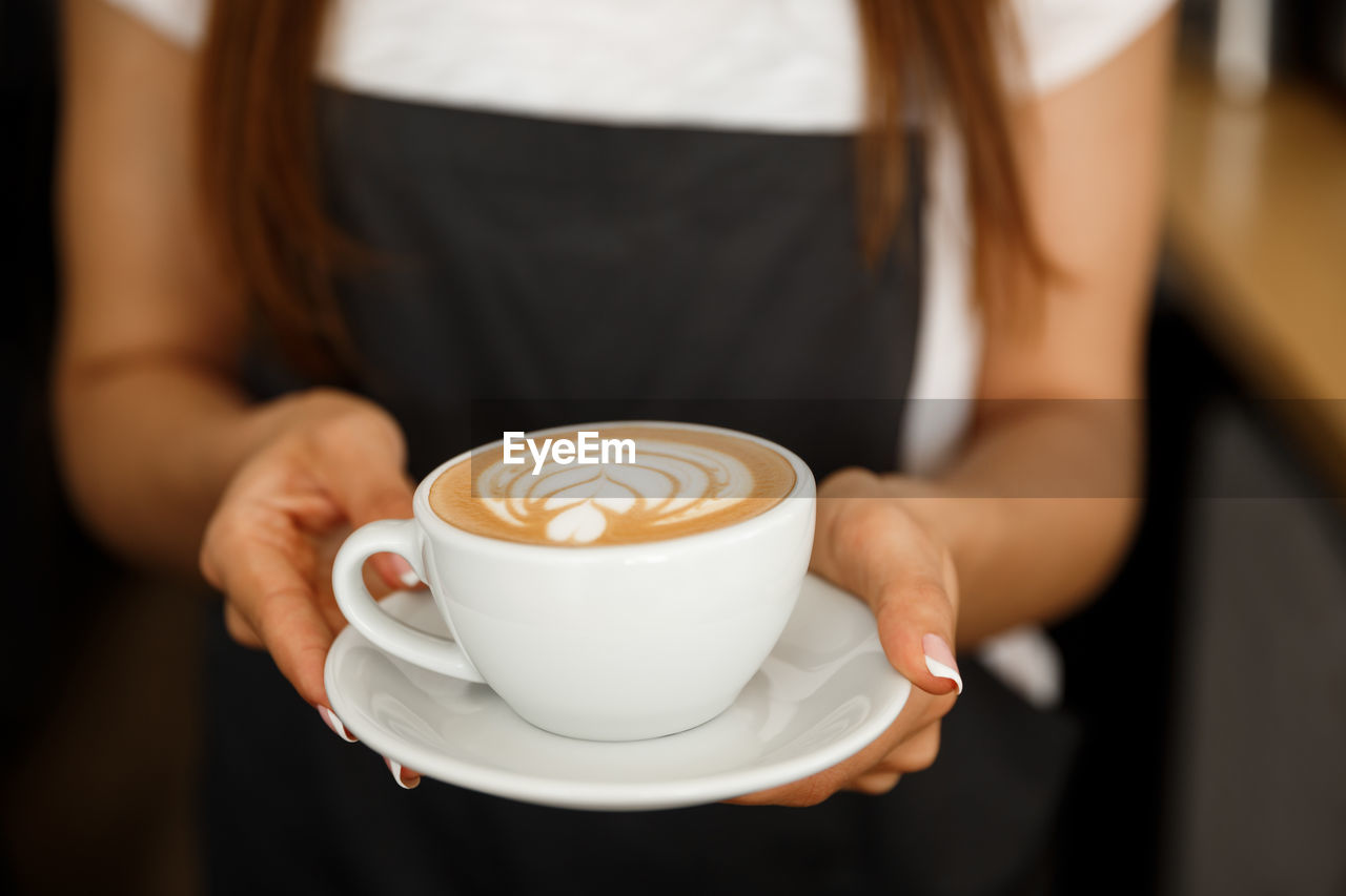 midsection of woman holding coffee on table