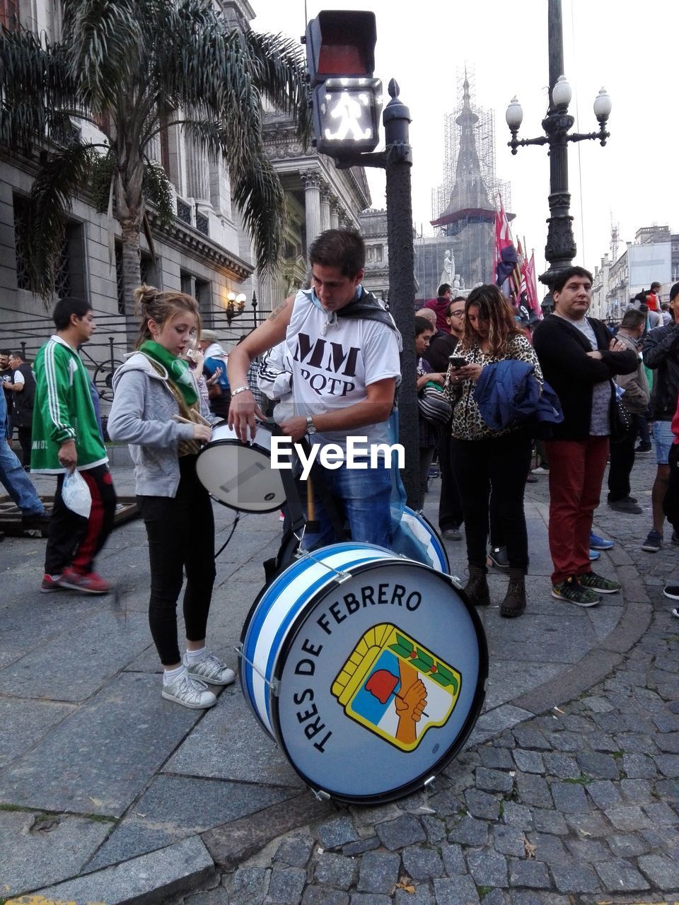 PEOPLE STANDING ON STREET WITH CITY IN BACKGROUND