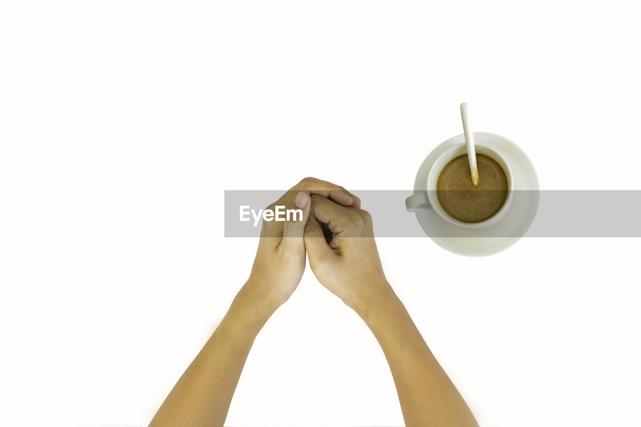 Cropped hands of woman by coffee cup on white background