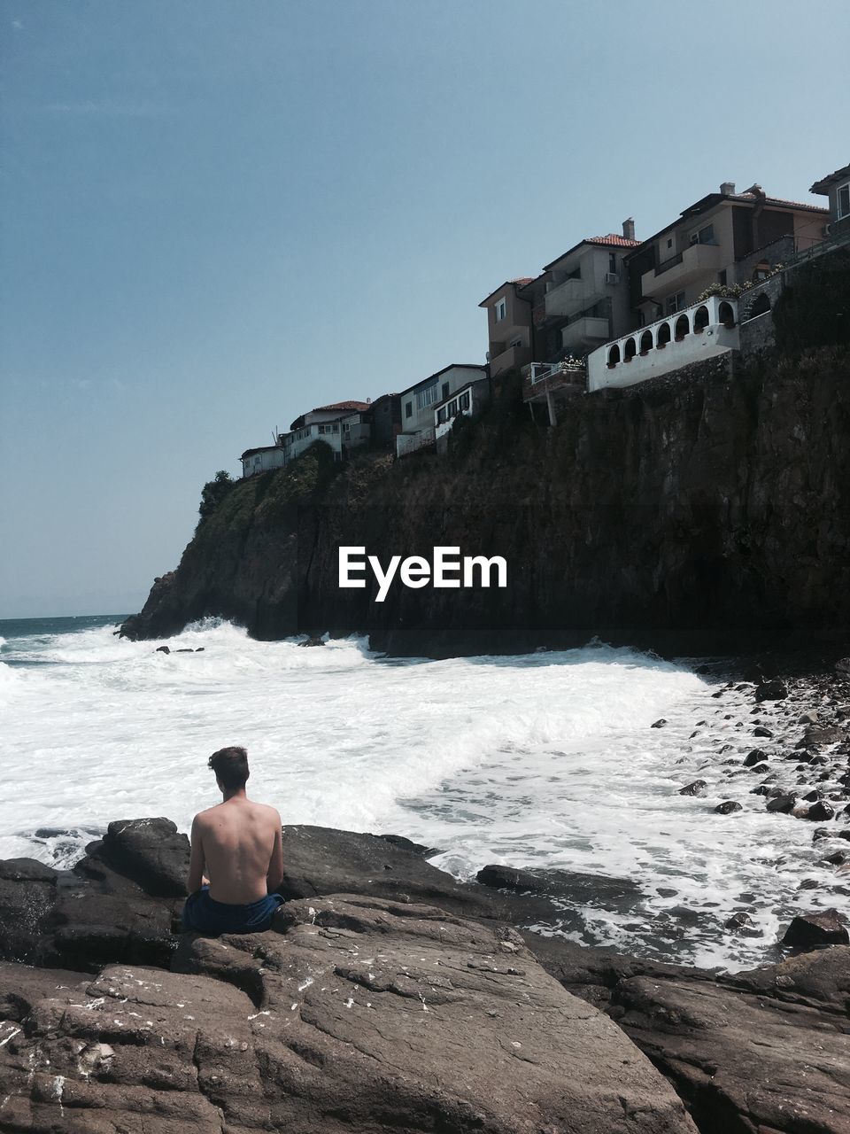 Man sitting on rock against sea