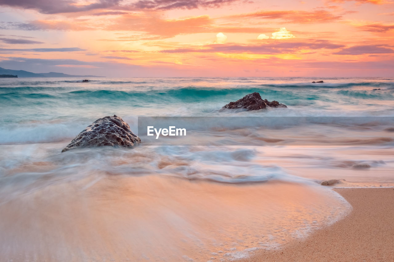 Scenic view of sea against dramatic sky during sunset