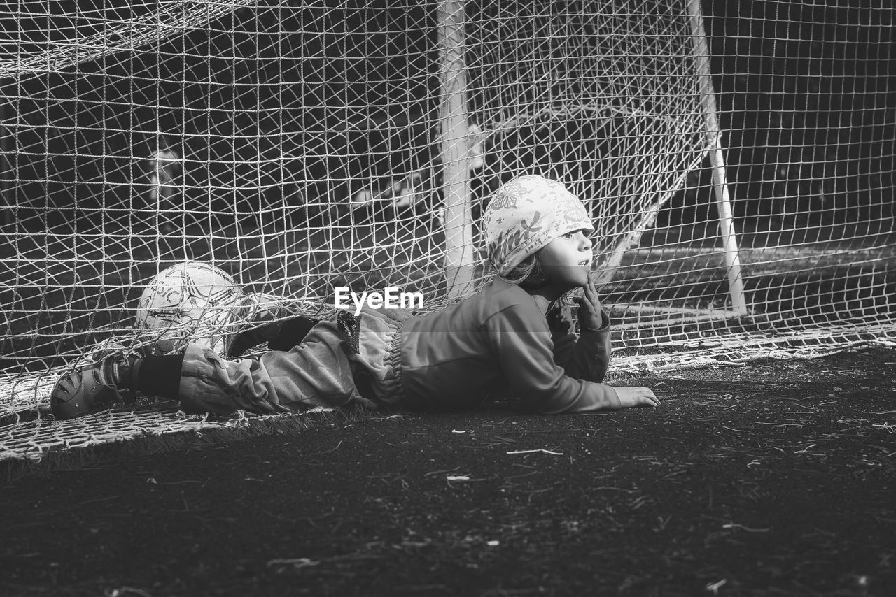 Playful boy lying on playing field in soccer goal