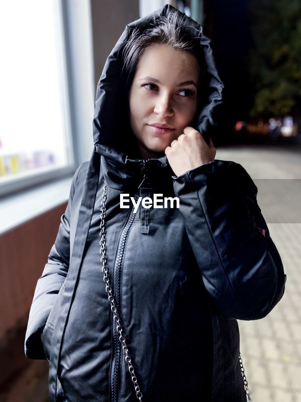 PORTRAIT OF SMILING YOUNG WOMAN STANDING AGAINST BLACK OUTDOORS