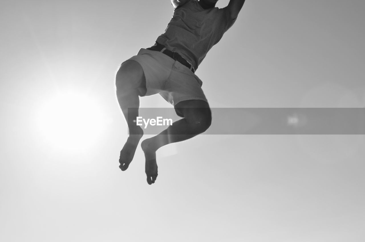 LOW ANGLE VIEW OF MAN JUMPING AGAINST THE SKY