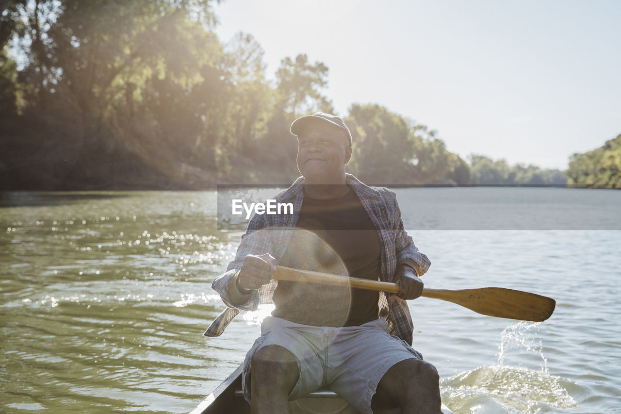 Man rowing on lake against sky