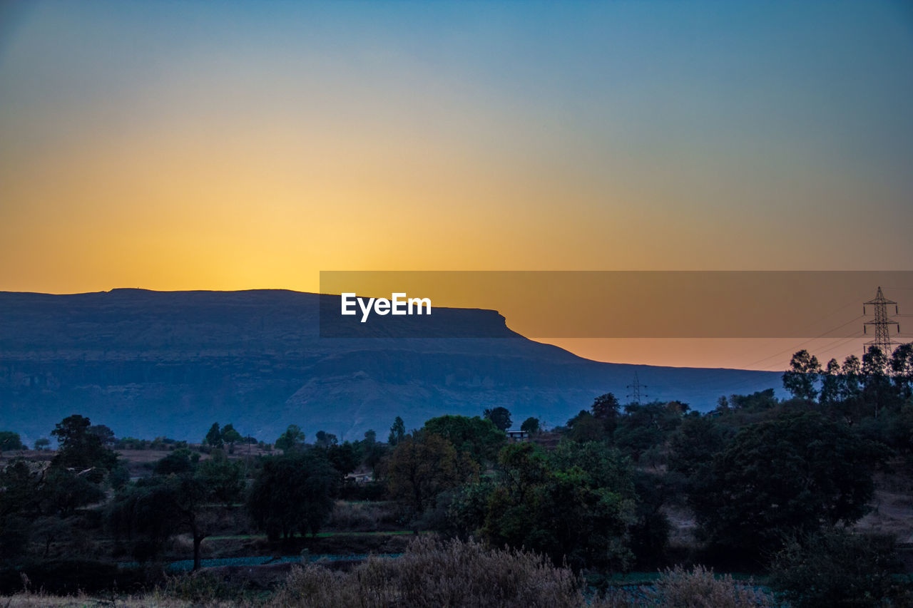 Scenic view of silhouette mountains against orange sky