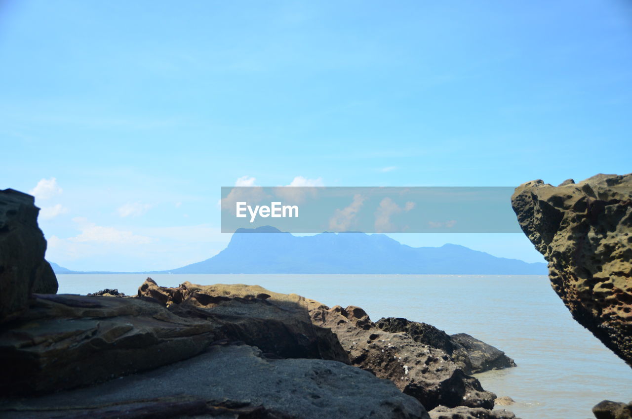 Rock formations in sea against blue sky