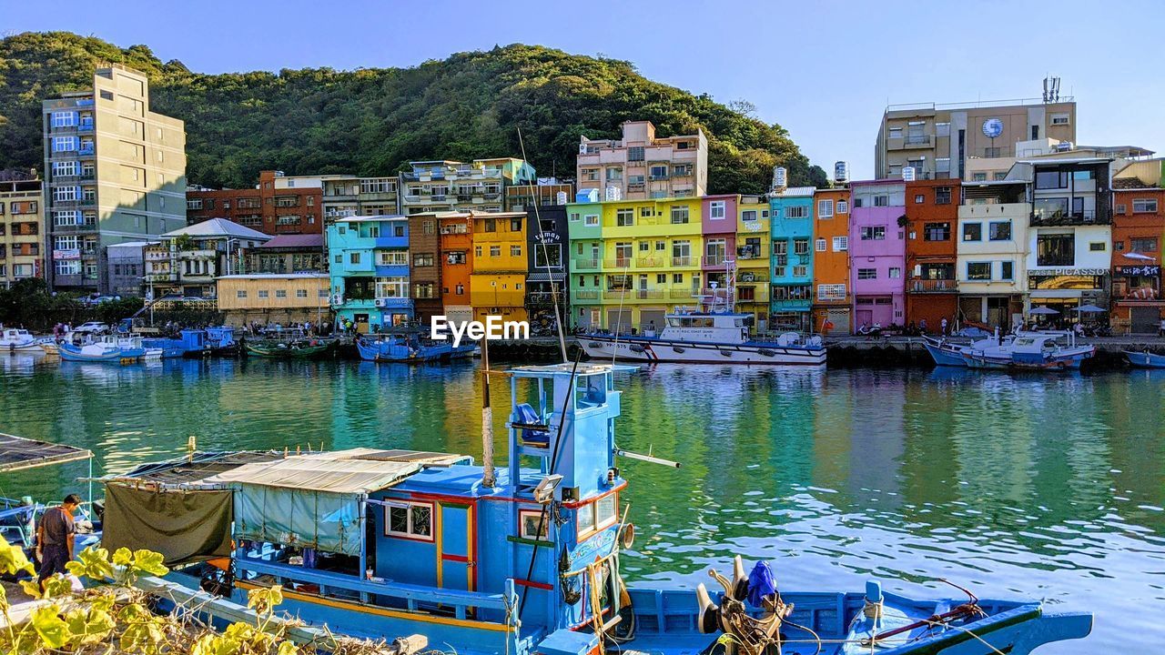 Boats moored in canal by buildings in city