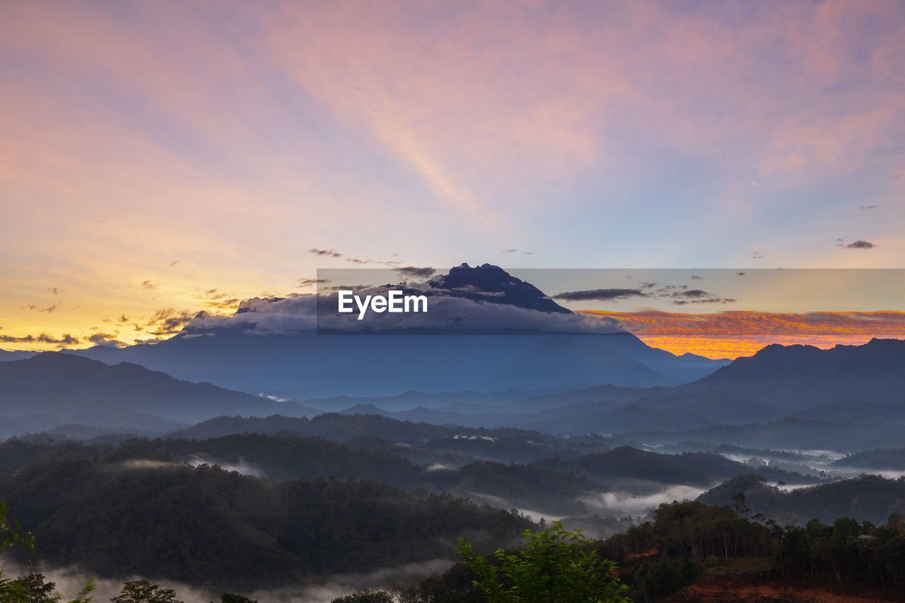 SCENIC VIEW OF MOUNTAINS AGAINST CLOUDY SKY DURING SUNSET