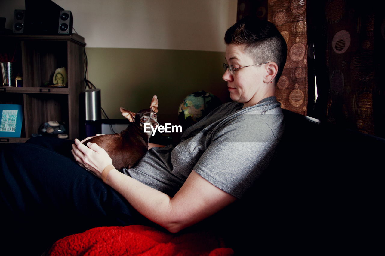 Woman sitting on sofa with dog at home