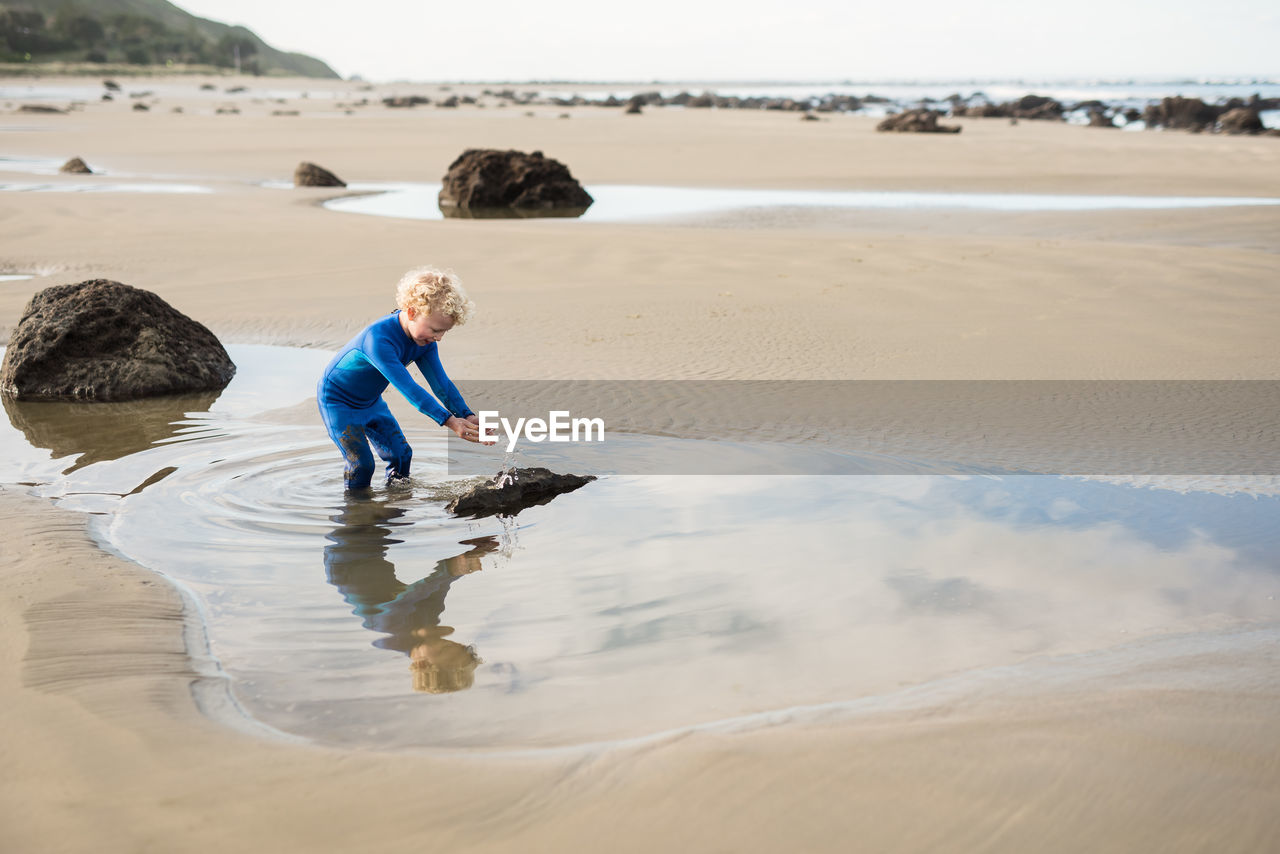 Young boy splashing water at new zealand beach
