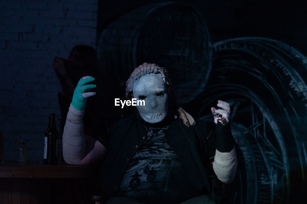 Man wearing halloween costumer sitting at table in darkroom