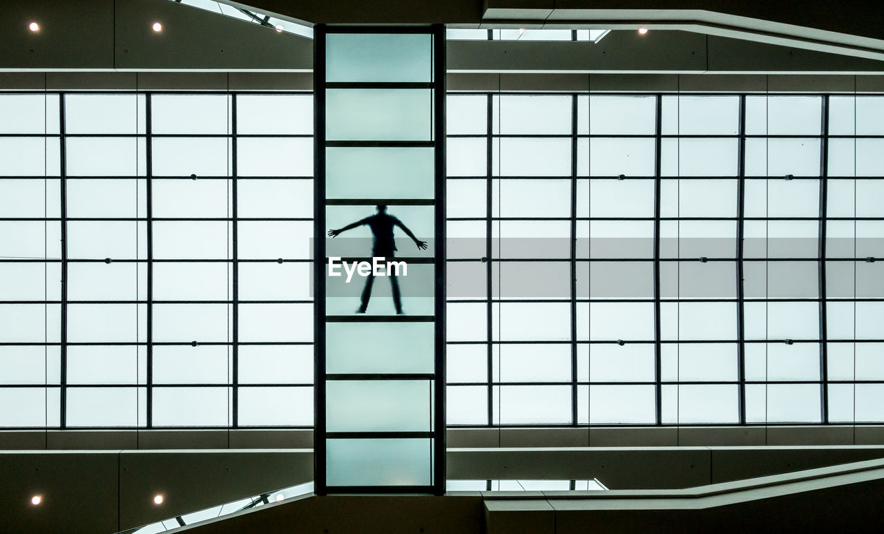 Silhouette man standing by window