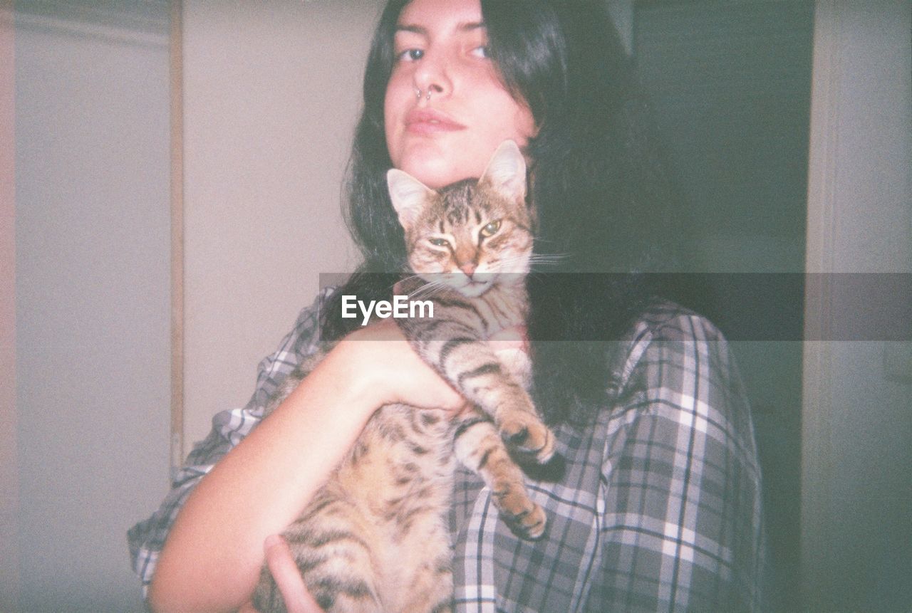 PORTRAIT OF WOMAN WITH CAT AGAINST BLACK BACKGROUND