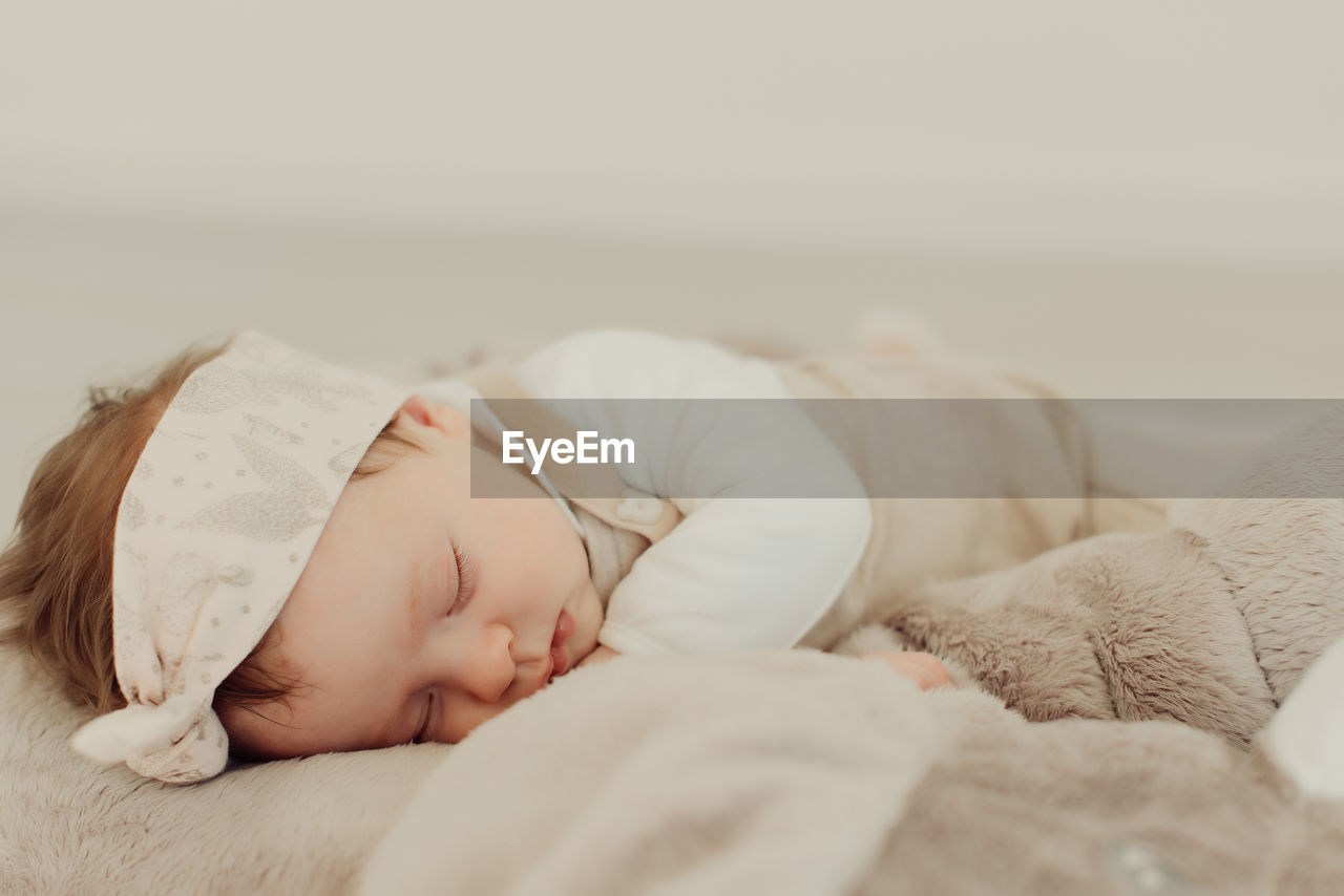 Cute baby girl sleeping on bed at home