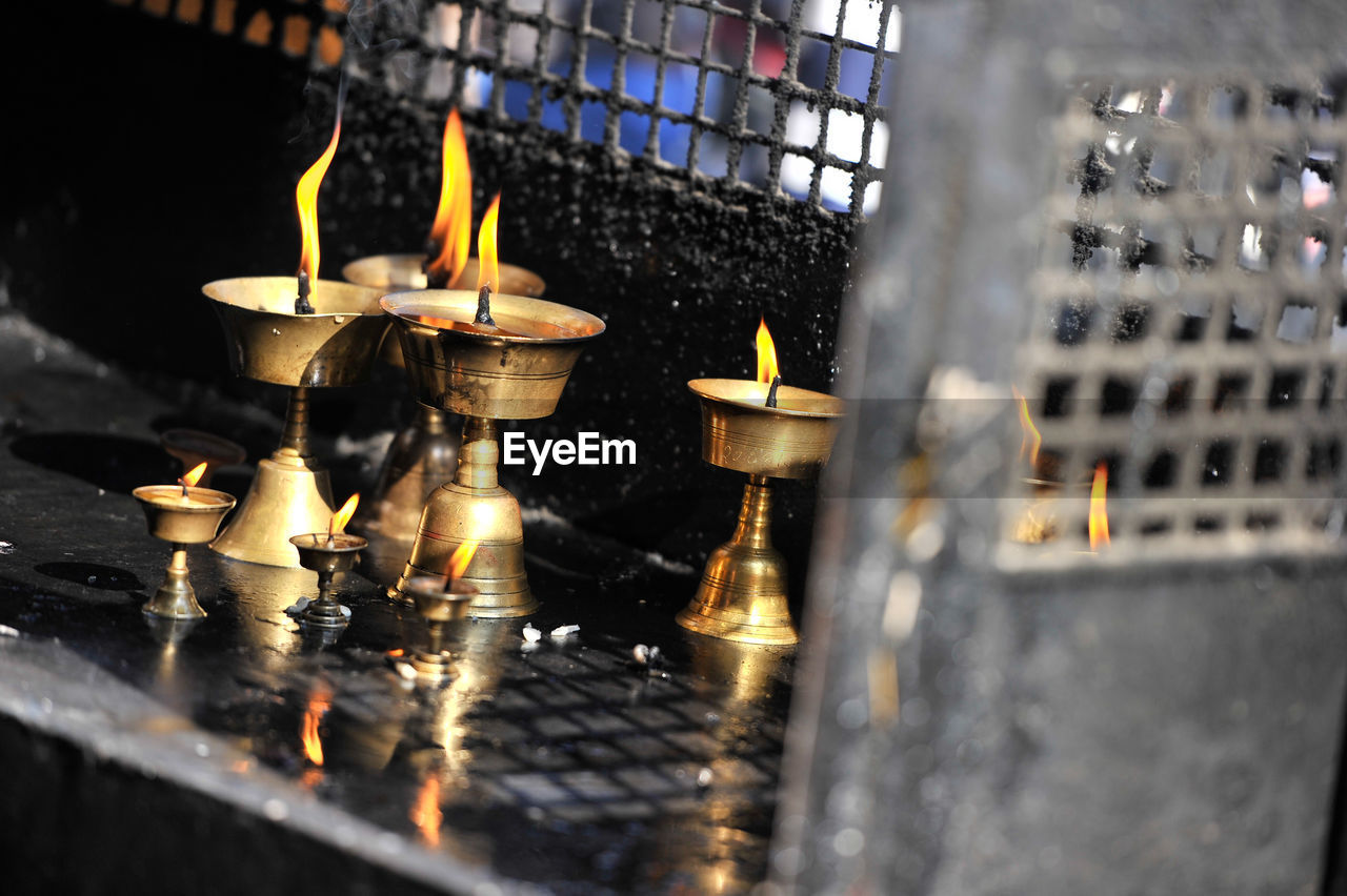 CLOSE-UP OF LIT CANDLES ON METAL OUTSIDE TEMPLE