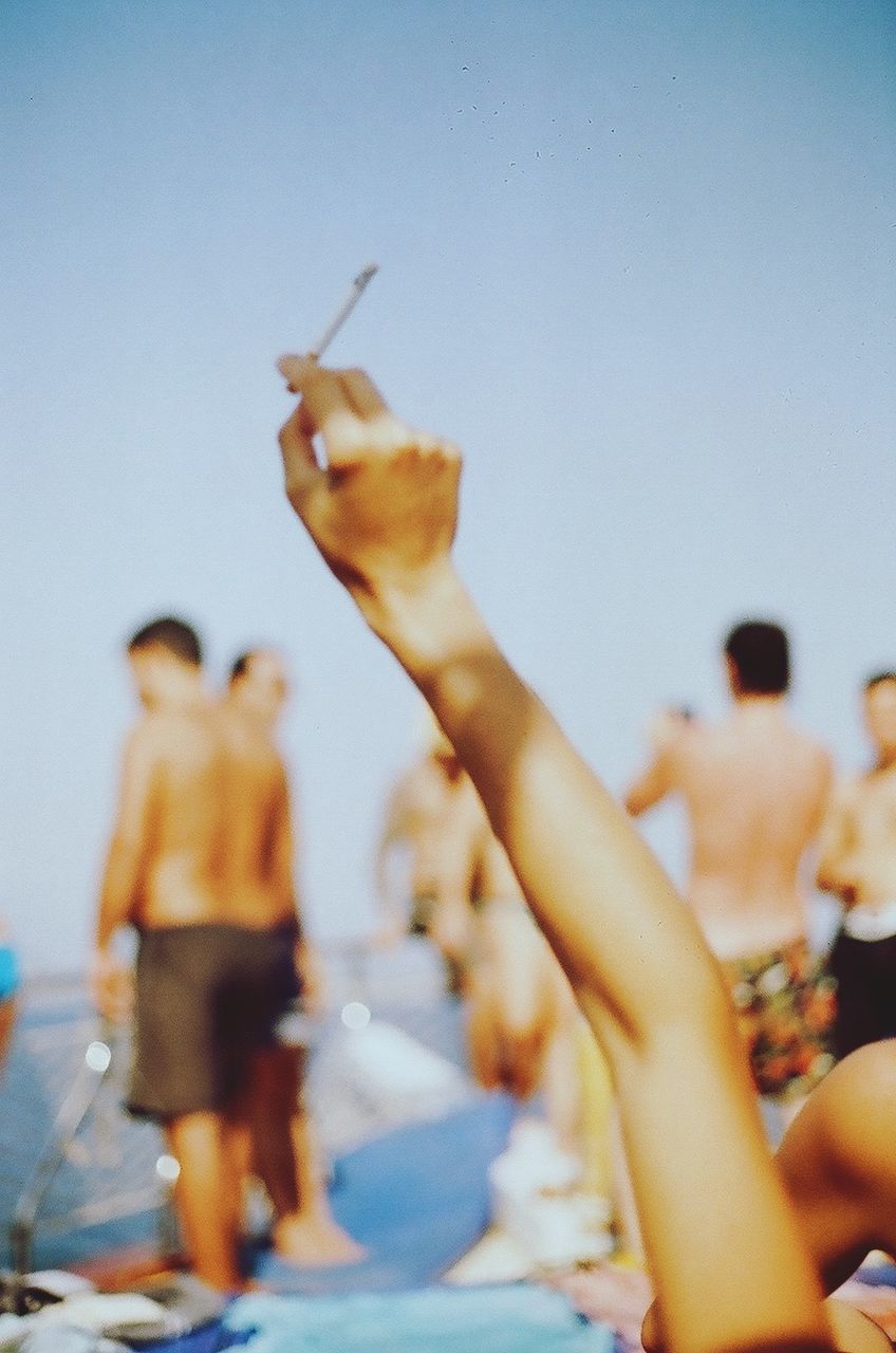Cropped image of woman holding cigarette against sky