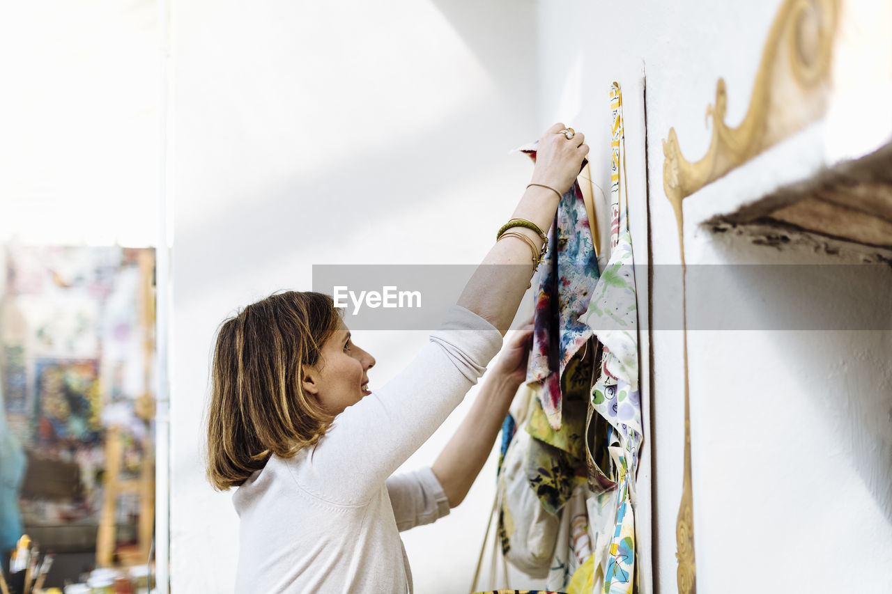 Female artisan hanging textile samples on wall in studio