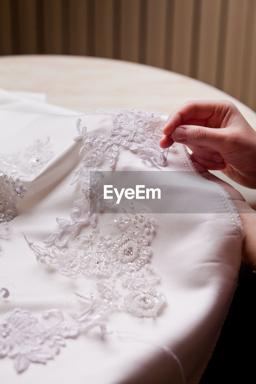 Cropped hand of woman stitching wedding dress