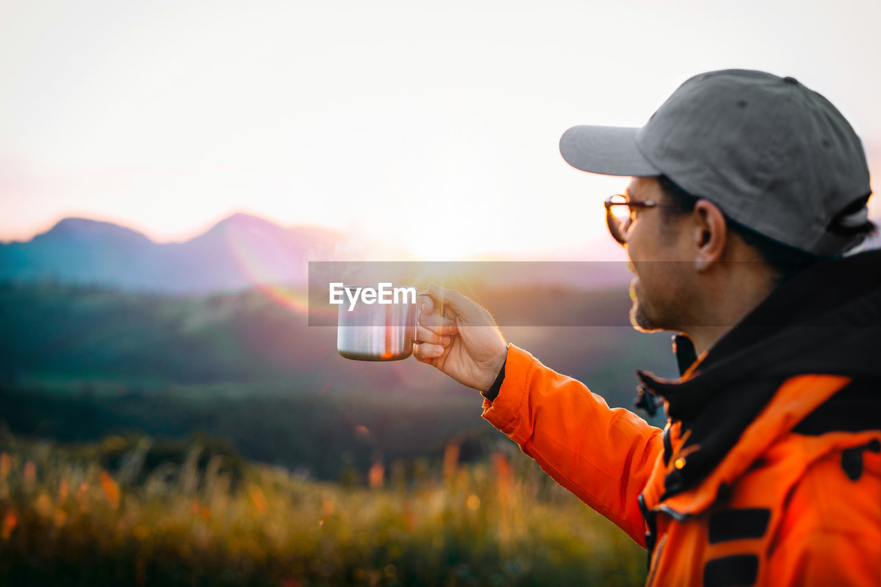 Man drinking coffee on mountain at sunrise