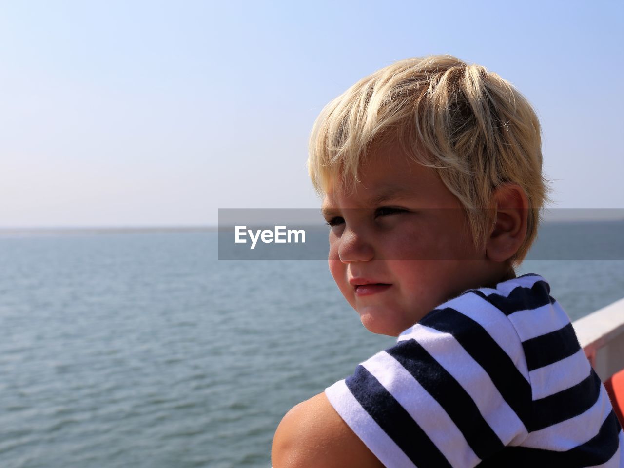 Portrait of boy looking at sea against clear sky