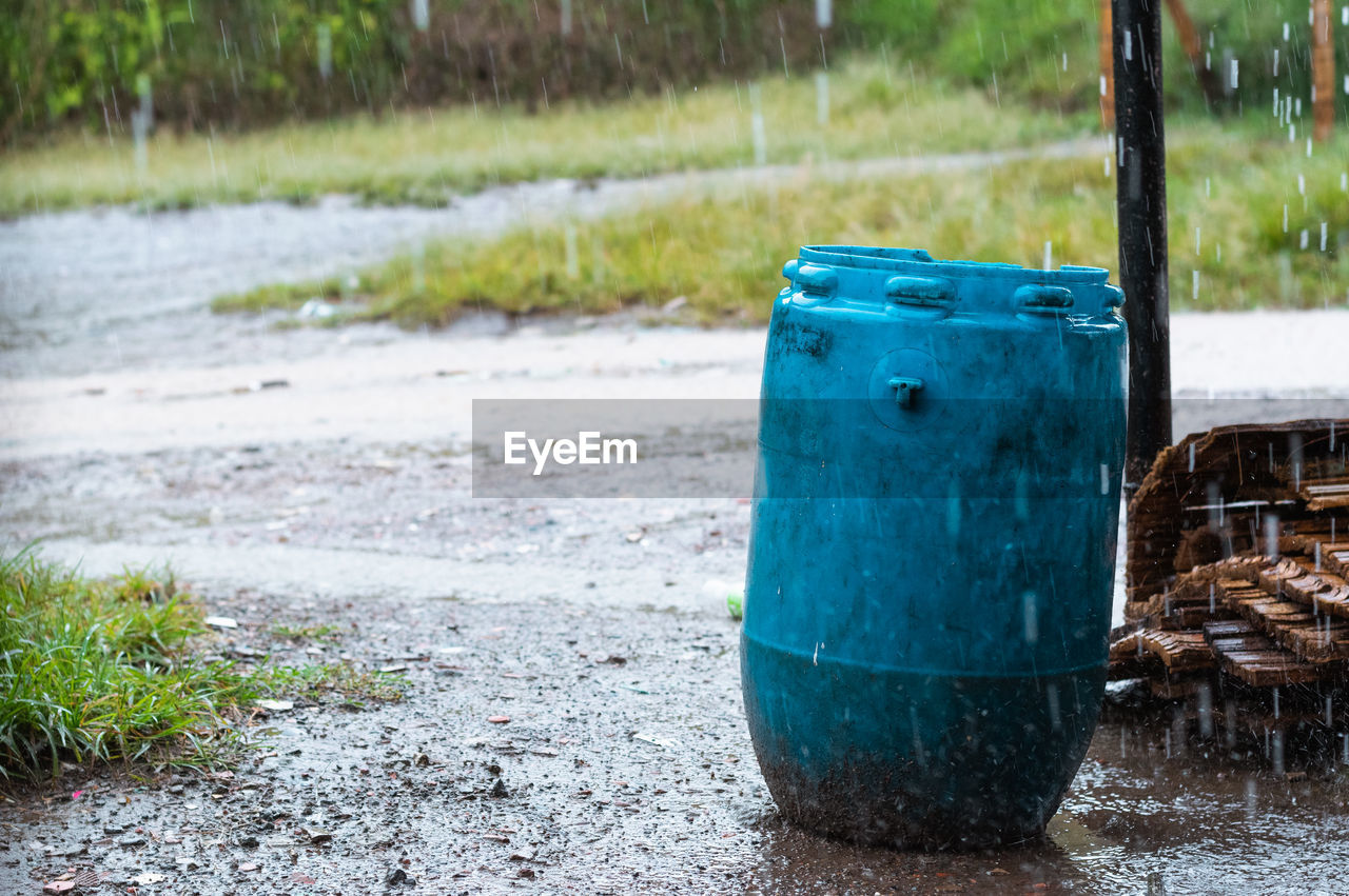 Blue trash can placed in the middle of a dirt road in a poor neighborhood, placed in the middle 