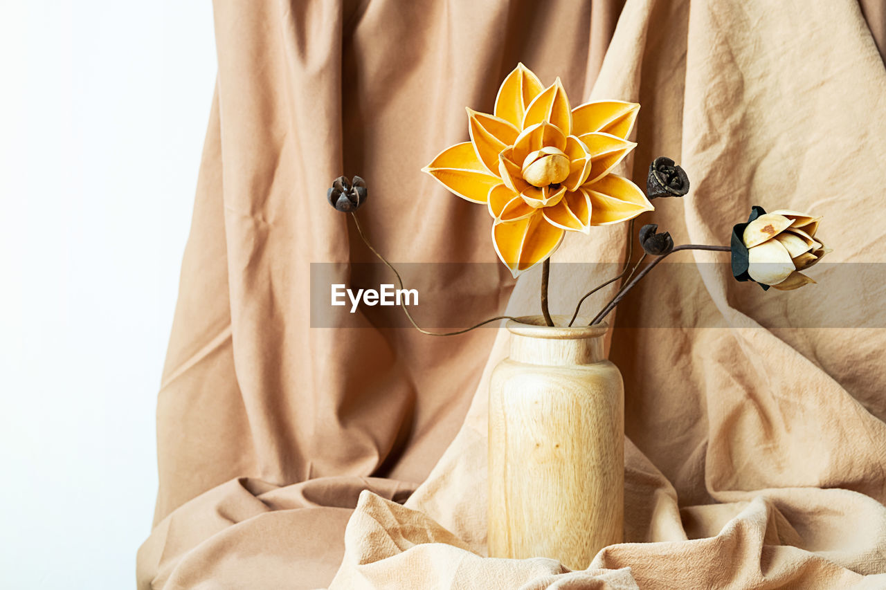 Dried flowers in wooden vase against draper. monochromatic modern still life.