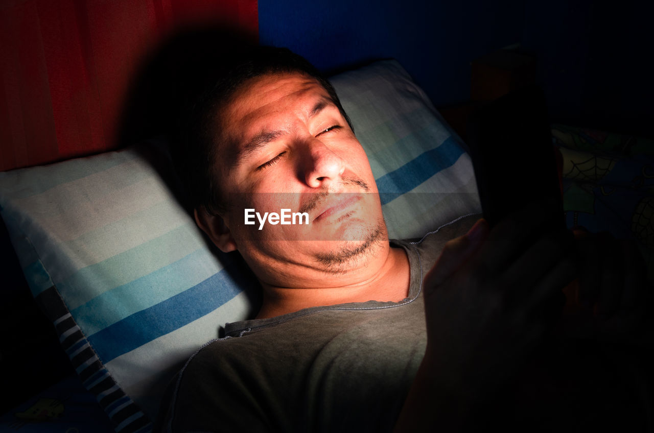 Man using mobile phone while lying in bed