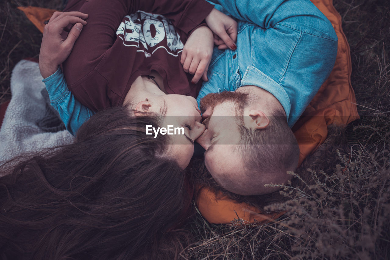 High angle view of couple kissing lying on grass outdoors