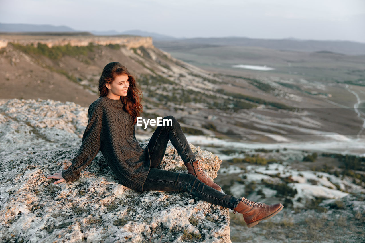 side view of young woman standing on rock