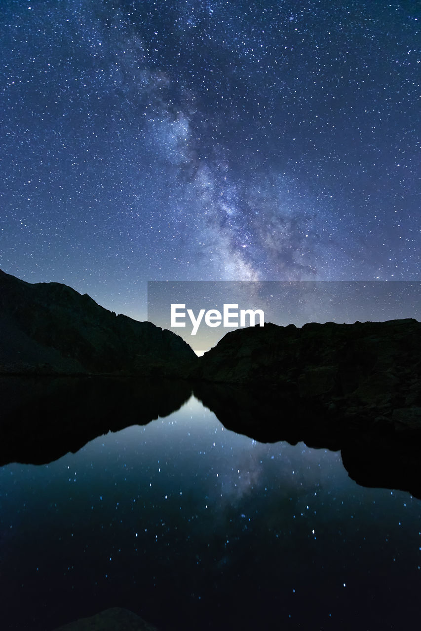 Scenic view of lake and mountains against sky at night