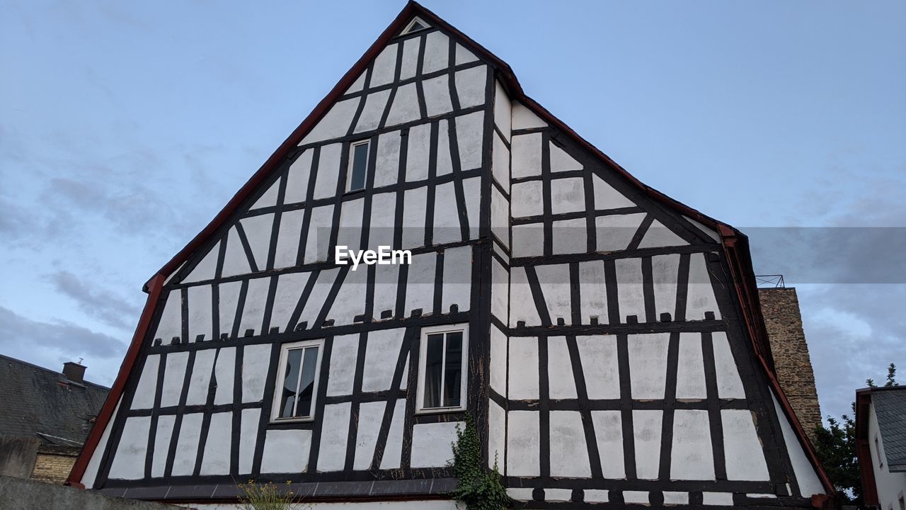 LOW ANGLE VIEW OF HOUSE BY BUILDING AGAINST SKY