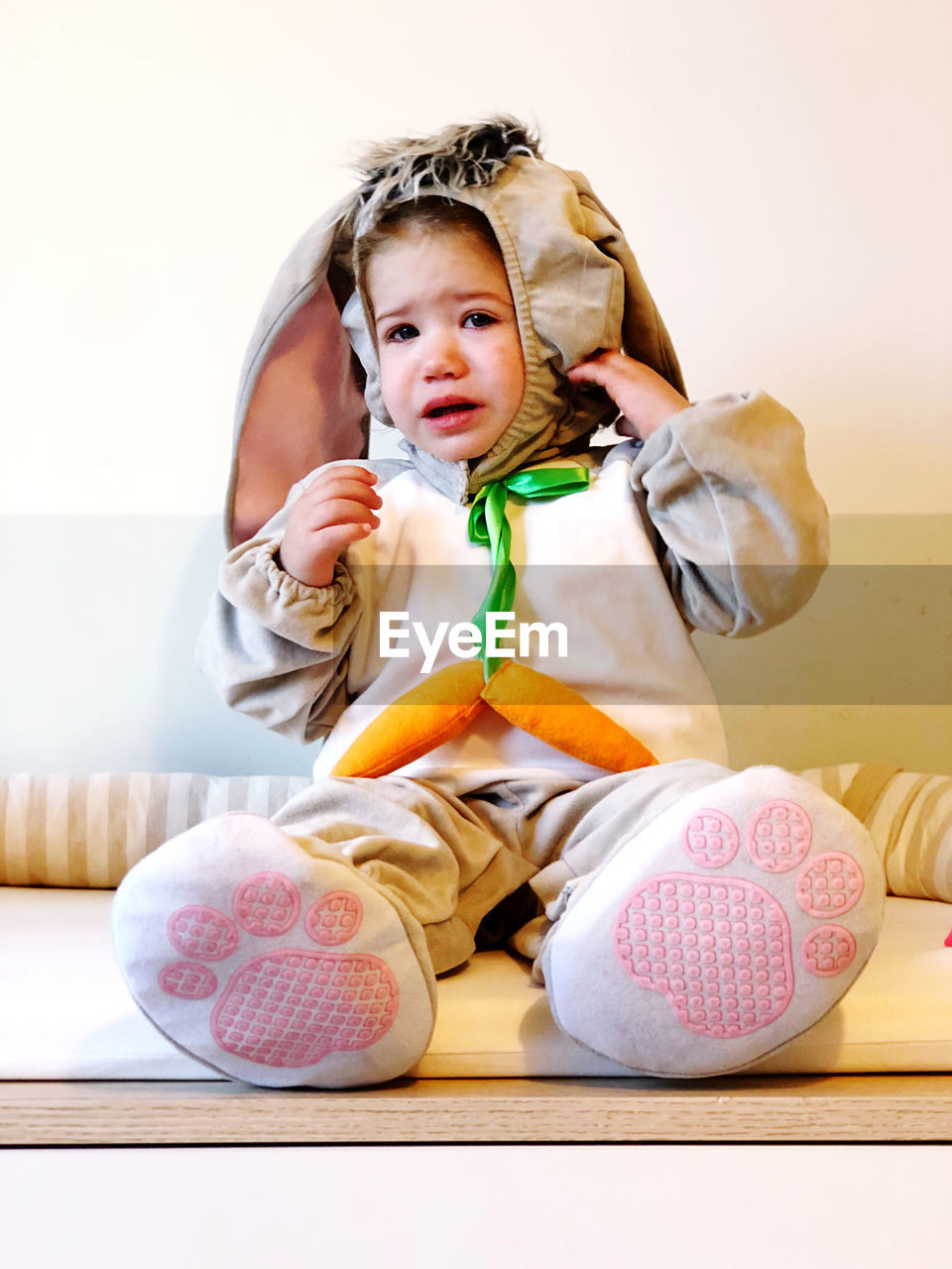 Cute girl sitting at home wearing a rabbit costume 