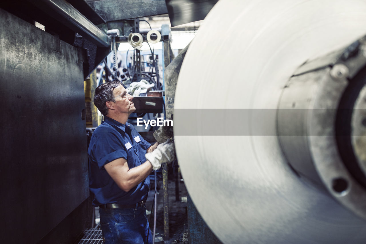 Worker using machine while working in steel mill