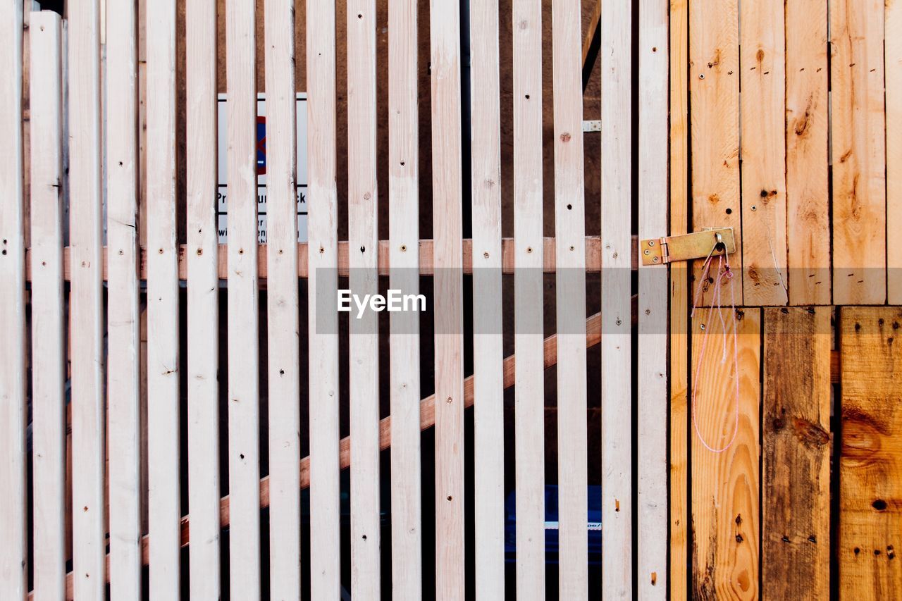 Close-up of wooden gate by fence