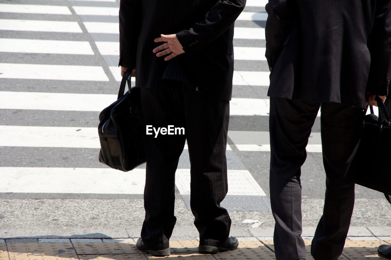 Low section of business people with luggage on road