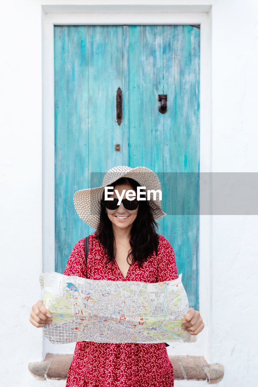 Content female traveler in sunglasses with map near old building in rhodes in greece