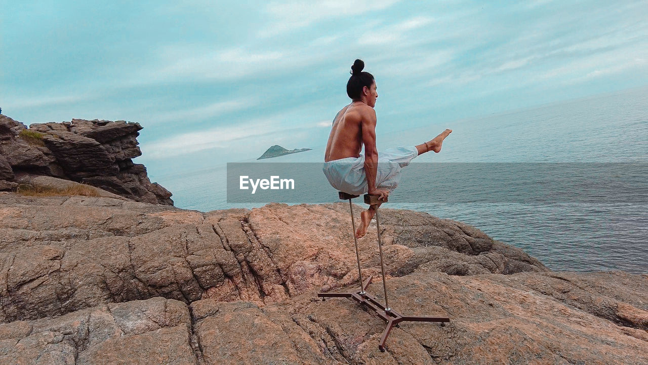 Young adult man doing circus acrobatics handstand on mountain in brazil during day light