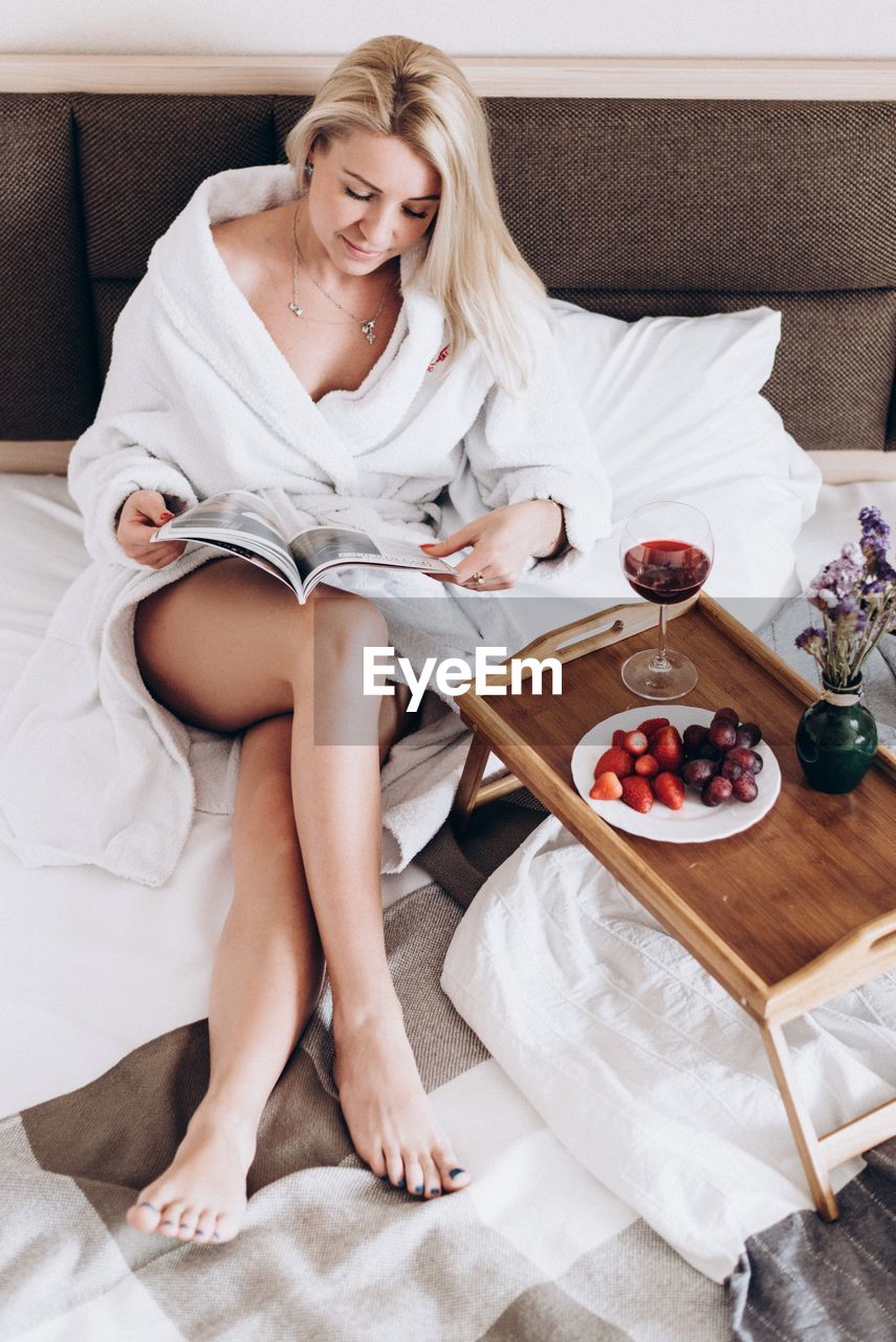 Woman in bathrobe reading magazine at home