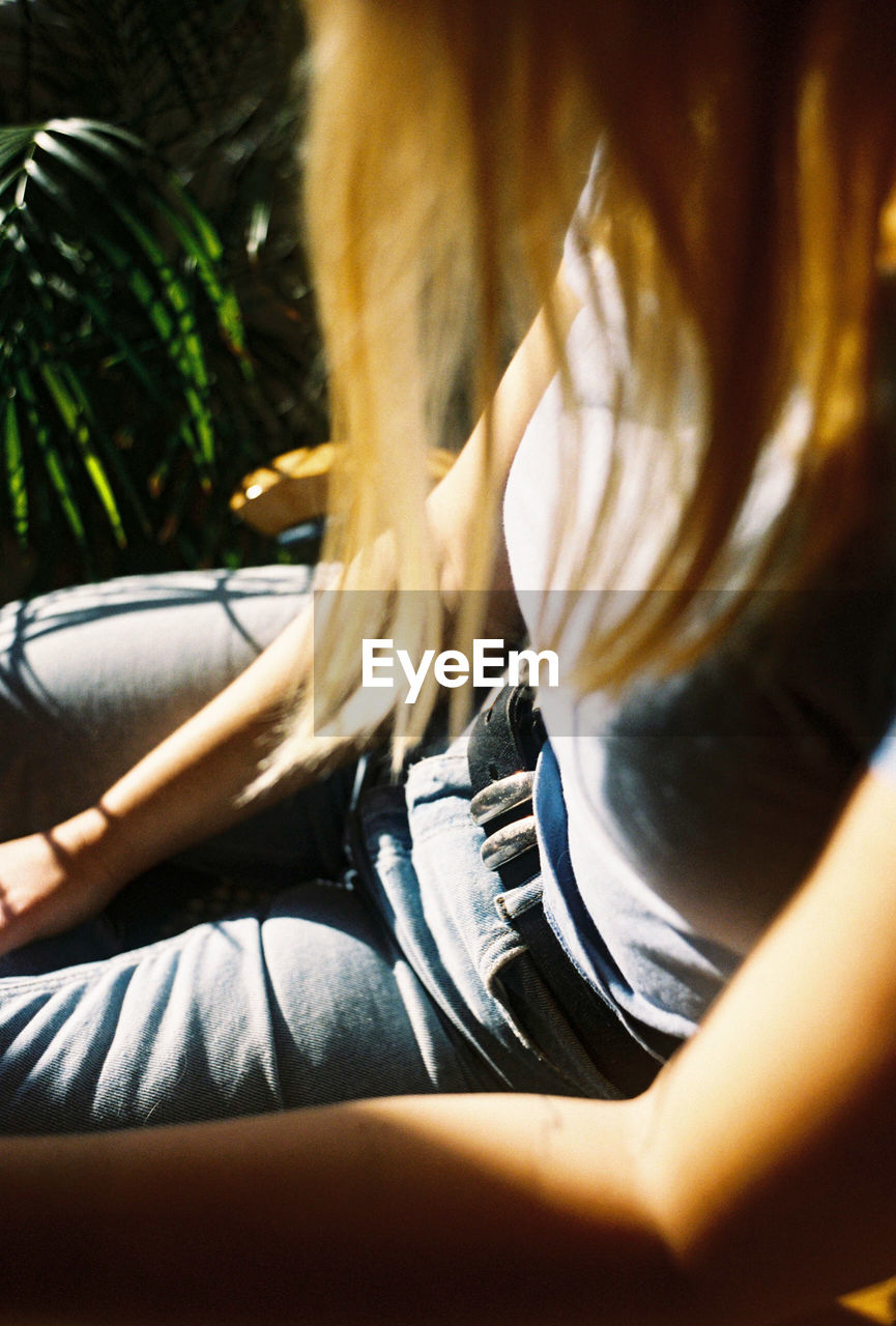 Midsection of woman sitting on chair by plant