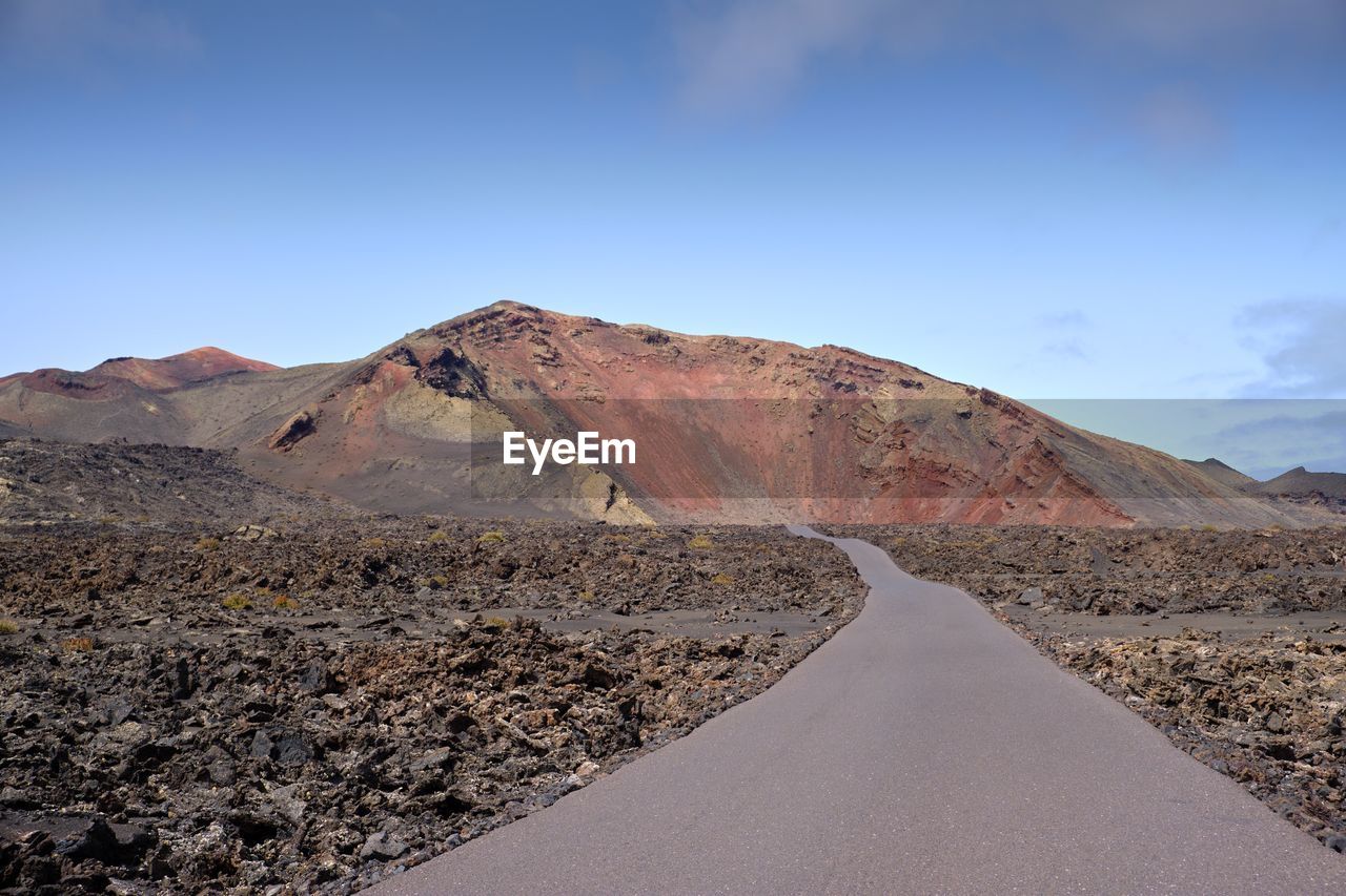 Road by mountain against sky